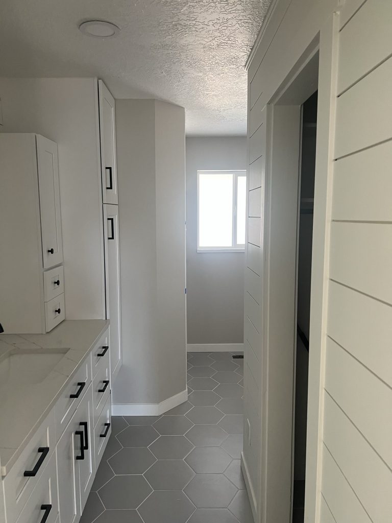 Renovated bathroom hallway and closet with tile flooring in a remodel by Black Diamond Builders.