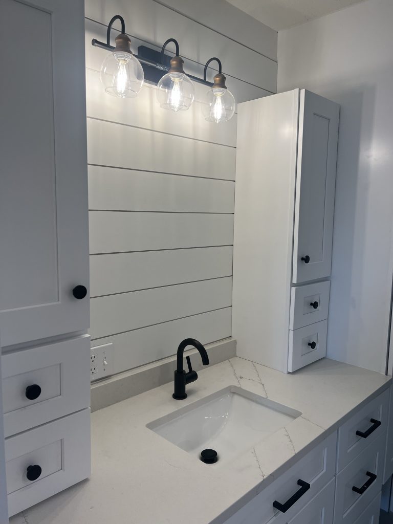 Newly installed bathroom vanity with a sink and modern lighting in a remodel by Black Diamond Builders.