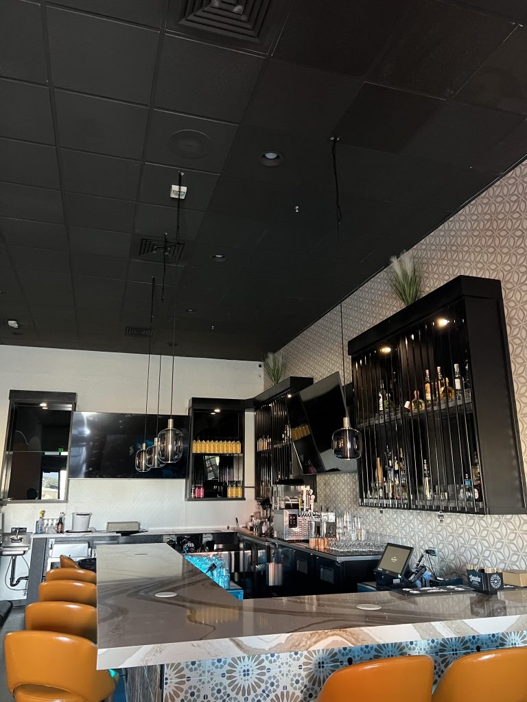 Interior of Sol Agave showing the bar area and seating, featuring contemporary lighting and a patterned tile design.