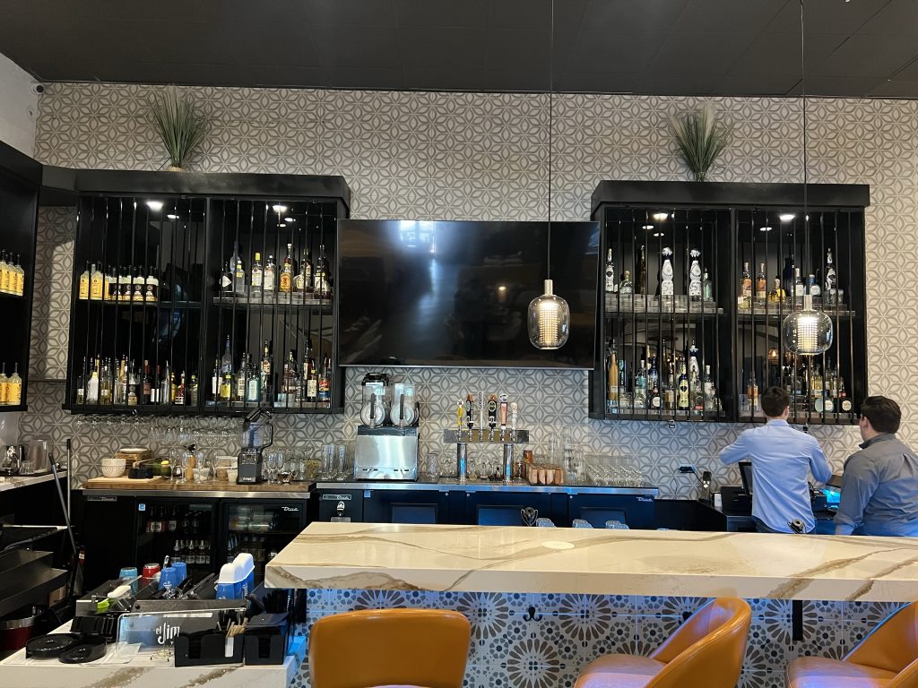 Bar shelving and countertop at Sol Agave, built by Black Diamond Builders, featuring hanging lights and a display of spirits.